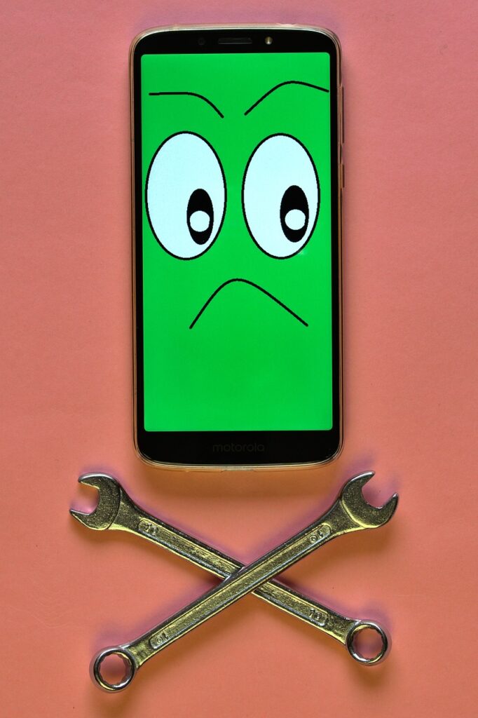 스마트폰 사용 중단을 의미하는 디지털 디톡스 이미지. 초록색 화면에 화난 표정 이모티콘과 X자 모양으로 교차된 렌치 공구